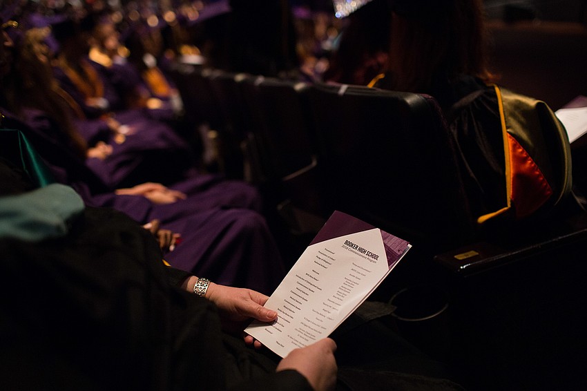 A graduate reads the program for the evening.