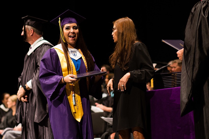 A student smiles for the audience as she gets her diploma.