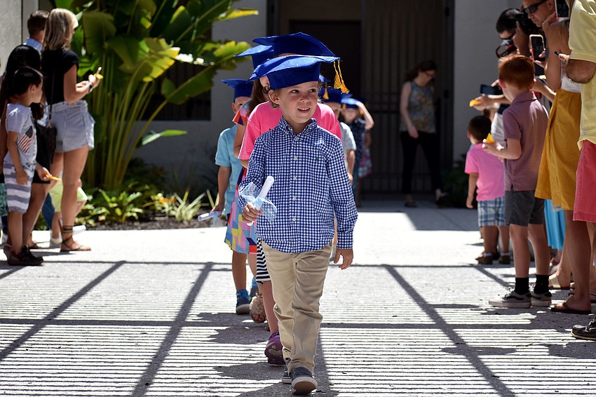 The graduates walk through the courtyard before tossing their caps in the air.