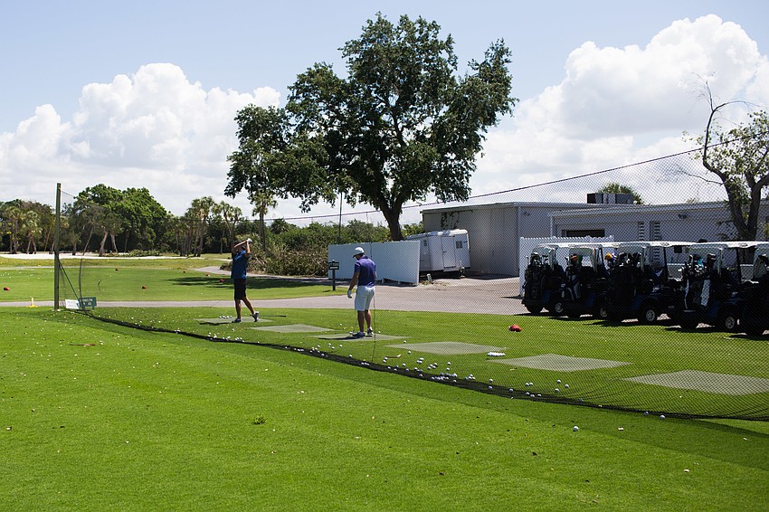 Golfers practice their swings before the start of the tournament.