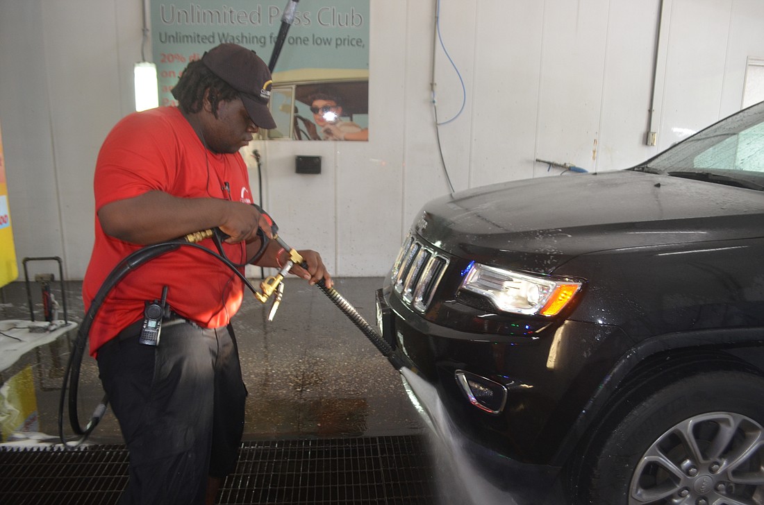 Dimitrius Adams, an employee of Clear Sunset Car Wash uses a pressure washer after they&#39;ve used a special bug wash to get the lovebugs off the front of the car.