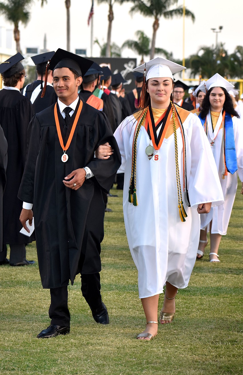 Girls and boys lined separate sides of the football field then walked to their seats arm in arm.
