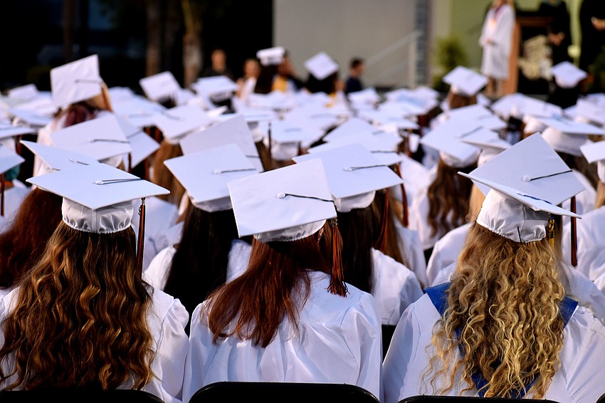 The graduates await the ceremony to begin as their classmates continue filing into their seats.
