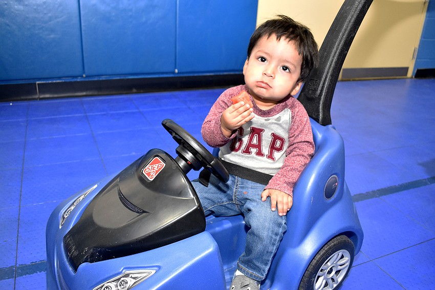 Jonathan Aguilar enjoys a snack while waiting in line with his mom.