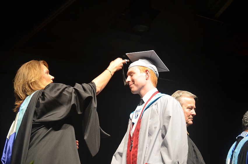 Principal Sharon Scarbrough moves Evan Lynch's tassel to the other side of his cap.