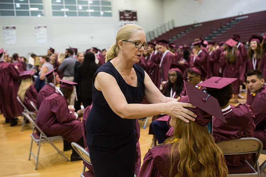 Debbie Berman fixes a graduate's hat.