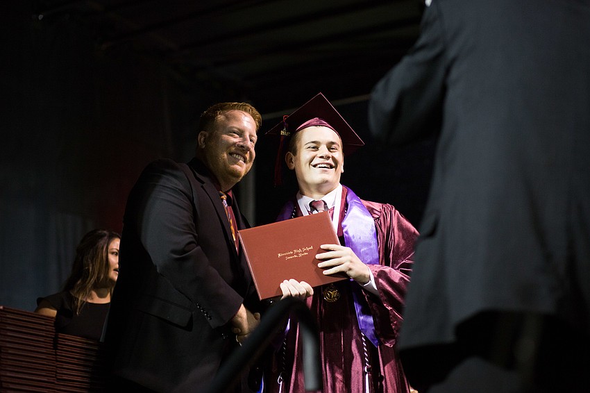 A graduate poses for a photo on stage.