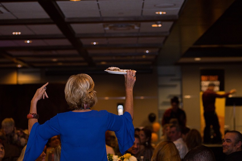 Judi Gallagher shows the guests her flop cake from the night before. Her triple-layer hummingbird cake sold for $800.