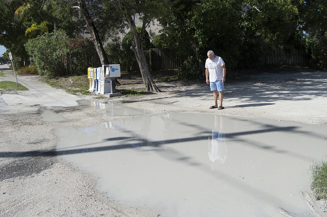 Steve Titunik stops in front of standing water at one of the parking lotâ€™s driveways after a few days of rain.
