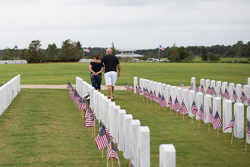 A couple walks out of the cemetery after visiting their loved one's stone.
