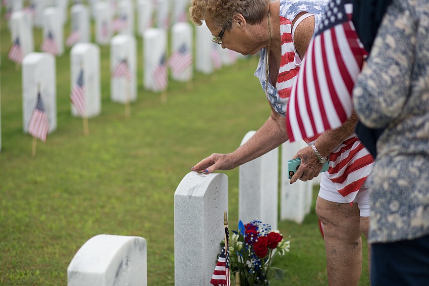 Paula Decker places coins on her husband's stone.