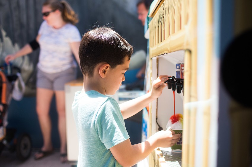 Dylan Sato pours cherry syrup on his Kona ice.
