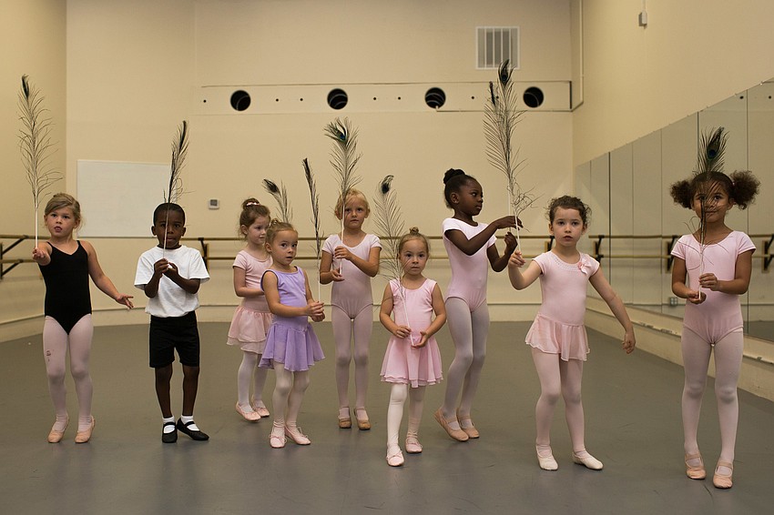 The dancers line up with peacock feathers, waiting for the cue to dance with them.