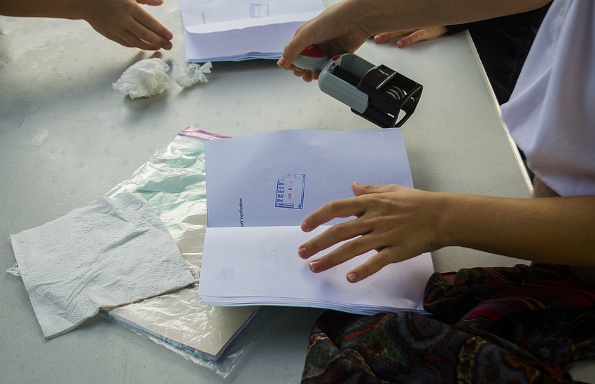 A student’s passports is stamped after she successfully navigated the baggage, information, medical and interview booths.