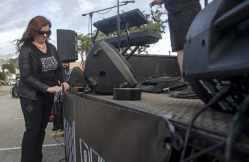 Stacy Dillard-Spahn attaches a Steel Relic banner to a stage in The Coral House parking lot. The band performed during the Welcome Thunder event.