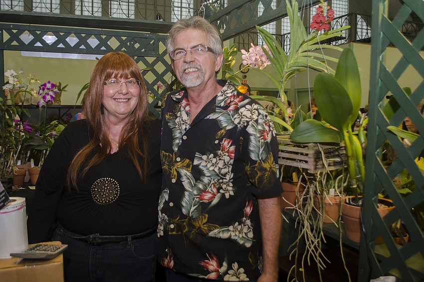 Paul and Patricia Phelps pose in front of their booth at the Sarasota Orchid Society'       s Symphony of Orchids festival and sale.