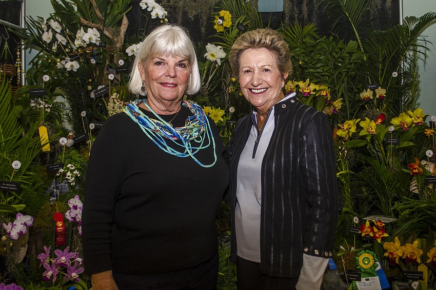 Janet Keown and JoAnn Britton of the Venice Orchid Society pose in front of their society'       s display.