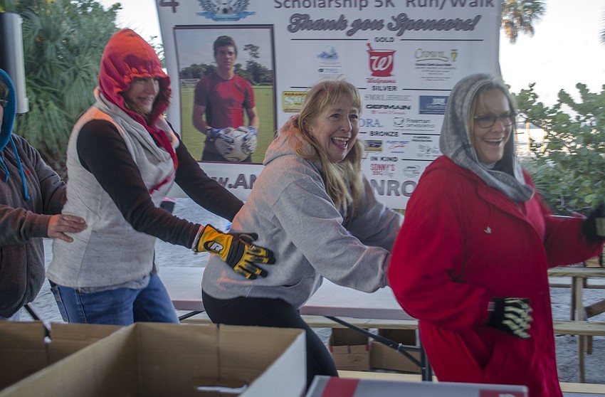 Karen Buren, Stacey Monroe and Sandy Eaton lead a conga line before the race. Many people were dancing and jumping to keep warm. Temperatures reached 37 degrees Sunday morning.