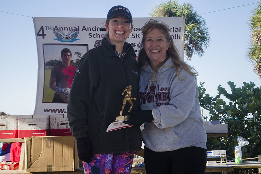 Female overall winner Phoebe Colvin Oehmig accepts her trophy from Stacey Monroe. Oehmig finished the race in 19 minutes, 58 seconds.