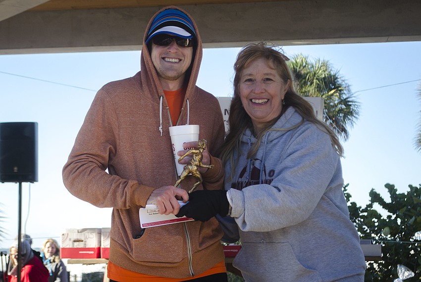 Male overall winner Taylor Henninge accepts his trophy from Stacey Monroe. Henninge finished the race in 18 minutes, 18 seconds.