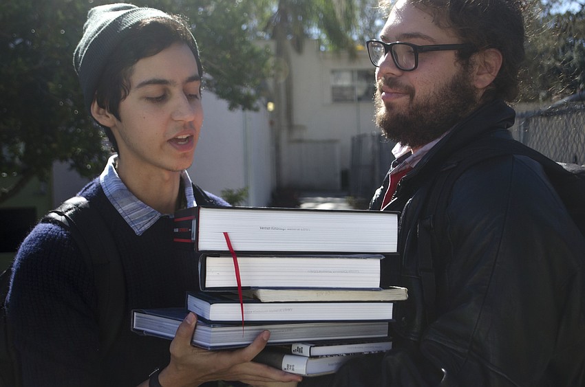 Austin O'    Reilley takes a pile of books from Jeremy Teran.