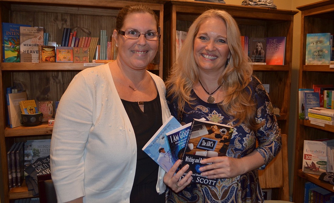Author D.D. Scott, Sarasota, and Cheri Christiansen, owner of Four Pillars, hold a number of Scott&#39;    s published books during her first writing workshop.