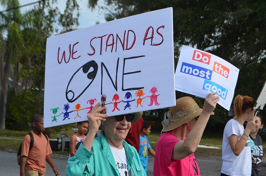 Patty Tun holds a sign as she walks down North Osprey Avenue.