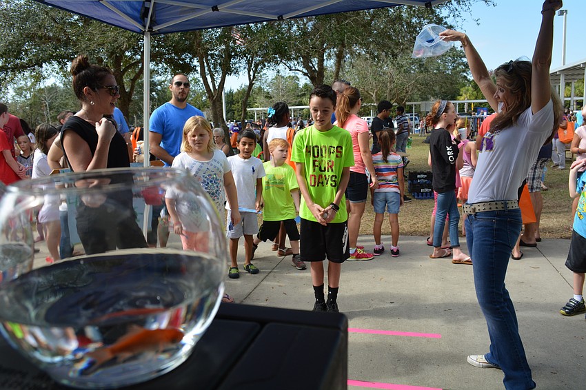 Cayden West, 11, successfully throws his ball into a fish bowl and wins himself an orange-and-black goldfish.