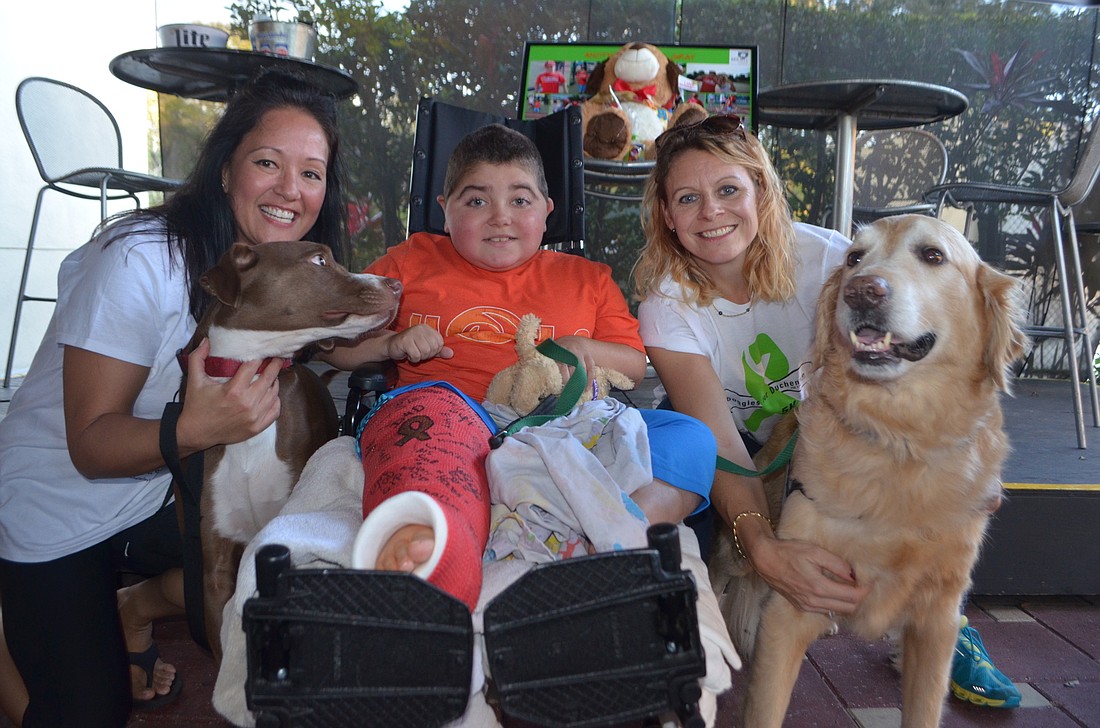 Rebekah Boos and her dog, Lola, Grayson Tullio and Monica Oberer and her dog, Hooch, mingle during a Doggies for Duchenne fundraiser to announce a beer named for the race.