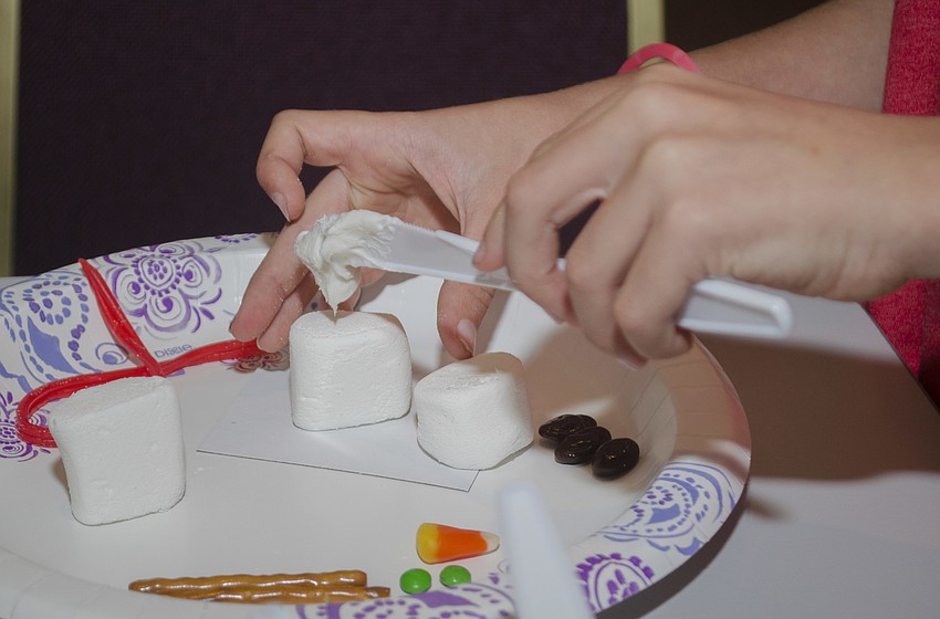 Jackson Mitchell makes a snowman out of marshmallows, icing and pretzels.