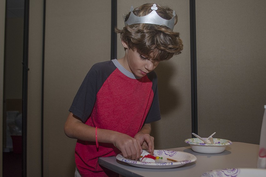 Jackson Mitchell makes a snowman out of marshmallows, icing and pretzels.