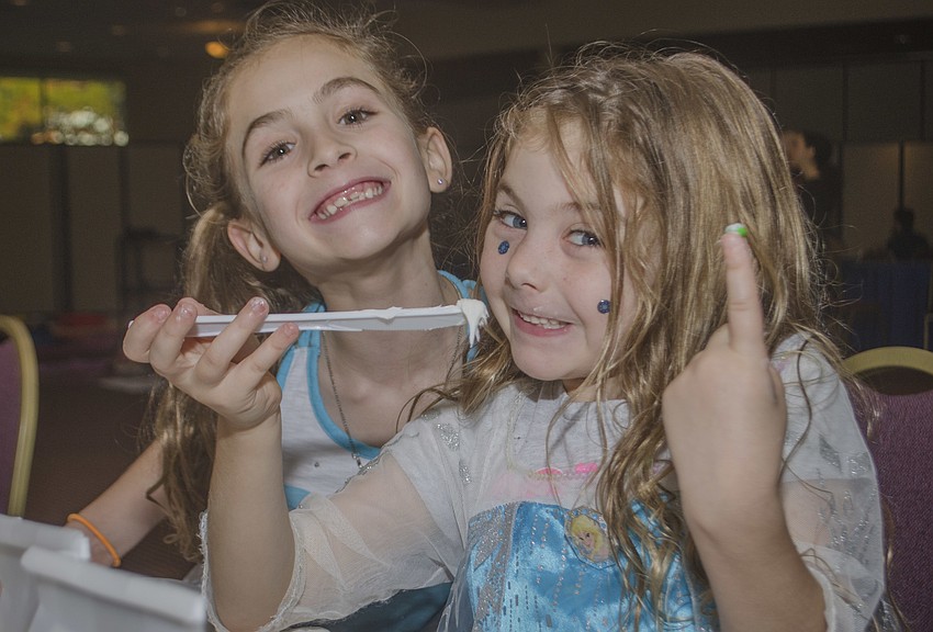Liza and Celia Collier make snowmen out of marshmallows, icing and pretzels.