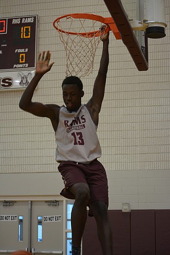 Malachi Wideman hangs on the rim after a dunk.