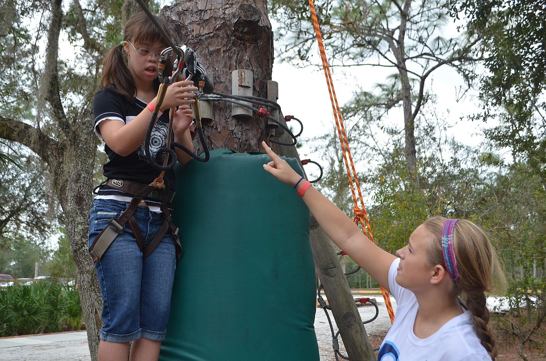 Natalie Pernia, 16, and Lilli Carlton, an ODA sophomore, help each other through the adventure course at TreeUmph!.