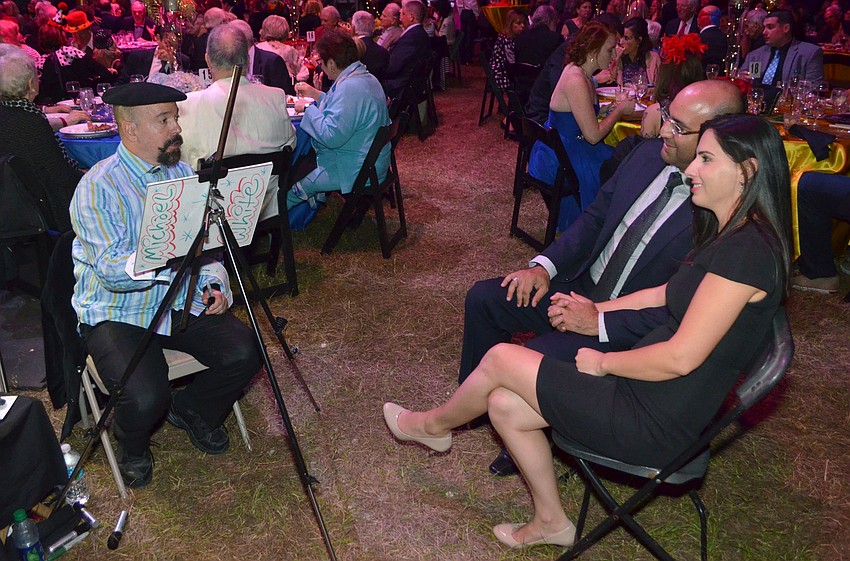 Michael James White draws a caricature portrait of Alex and Yona Elshimy.