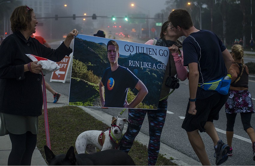 SueAnn Levin holds a sign with Bibi  Vehent as Julian Vehent stops for a kiss.