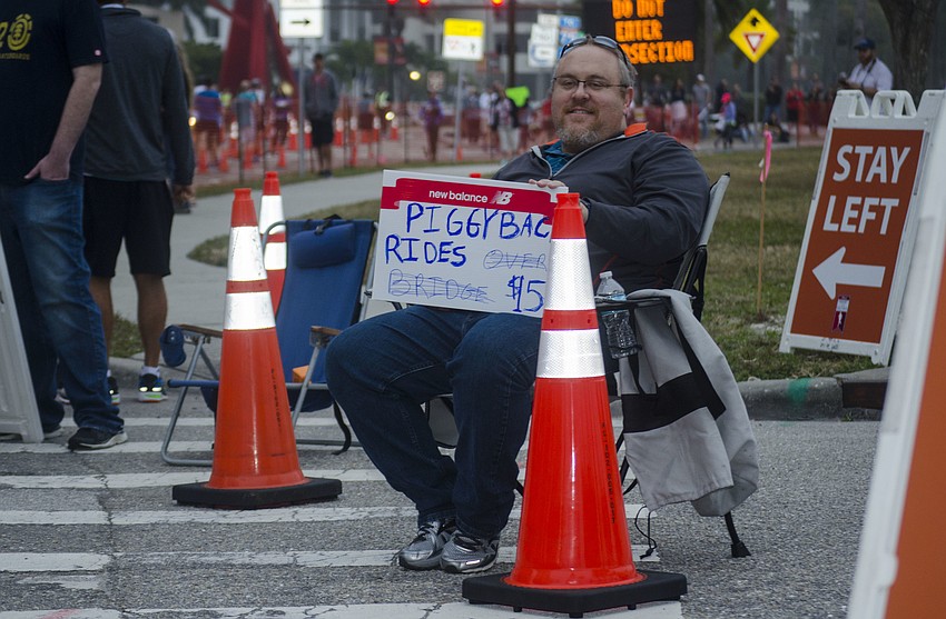 Matt Winer holds a sign advertising piggy back rides. The price increased as the race went on.