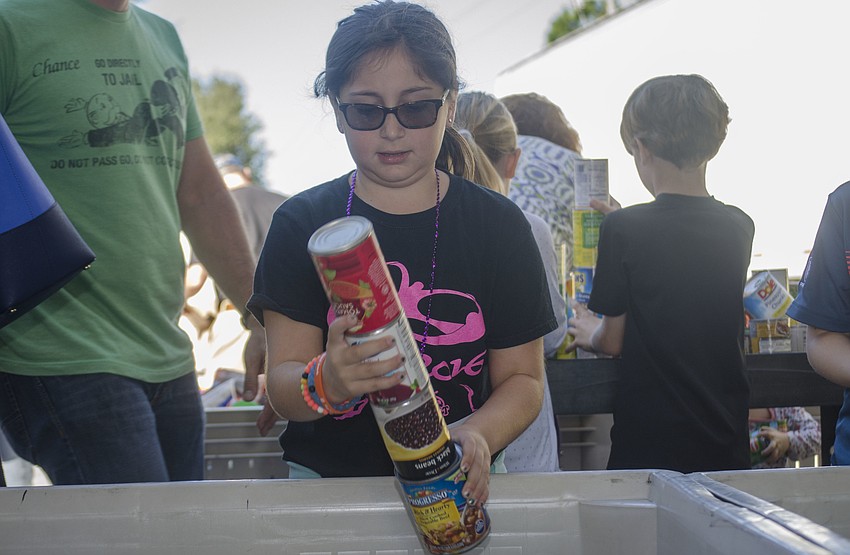Avery Portugal sorts cans at All Faith’s Food Bank.
