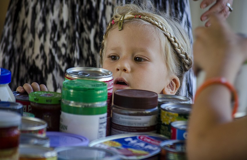 Raina Kurnov peeks over a cart loaded with canned goods.