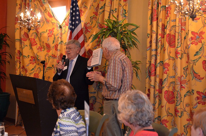 Murray Blueglass presents Alan Bandler with a book each member present signed. Bandler is stepping down from the club’s board after 12 years.