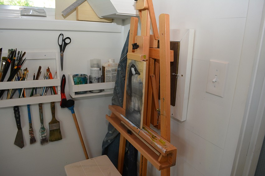Tim Davison has his easel tucked away against a wall and his brushes on the wall.