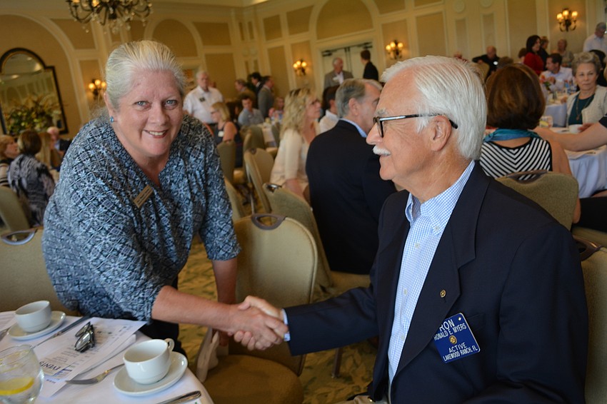 Michael Saunder'    s Mugsie Quinlan shakes hands with Rotarian Ron Myers.