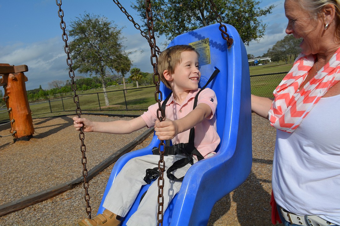 Six-year-old Easton Griffith, of Bradenton, enjoys a swing at Tom Bennett Park with his mother, Jennifer Griffith, club president of the Rotary Club of West Bradenton.