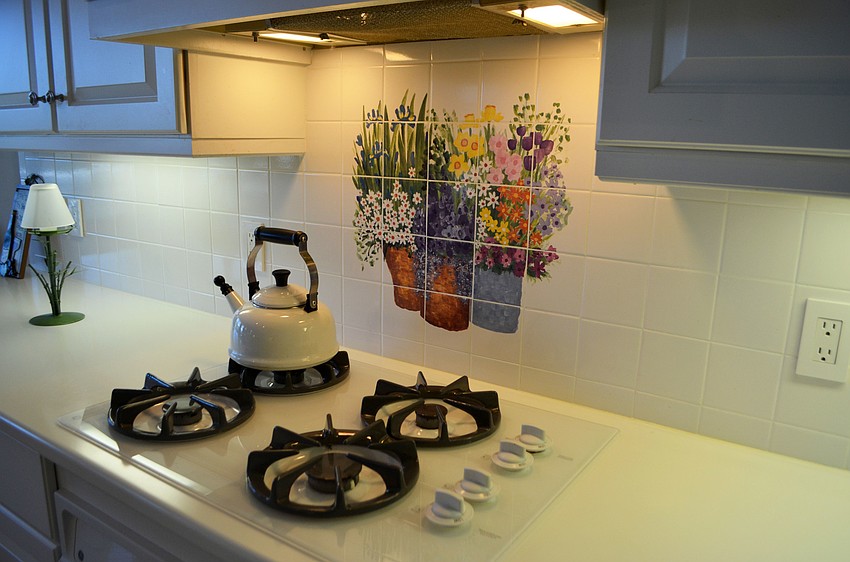 A floral tile painting rests above the stove in the kitchen.