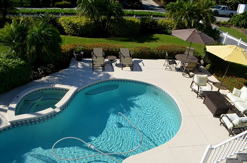 The pool deck is complete with plenty of seating and a hot tub.