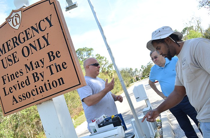 Watercrest Condominium Association staff John Coppenhaver, left, and Ricardo Taliaferro, right, update association board member Jerry Twiggs, center, about what they are doing to help keep the gate emergency-access only.