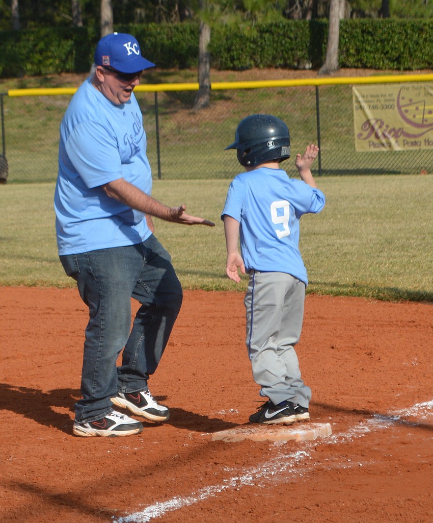 Assistant coach Mike Kennedy gives Nolan Lane some love after Lane reached first base for the Royals.