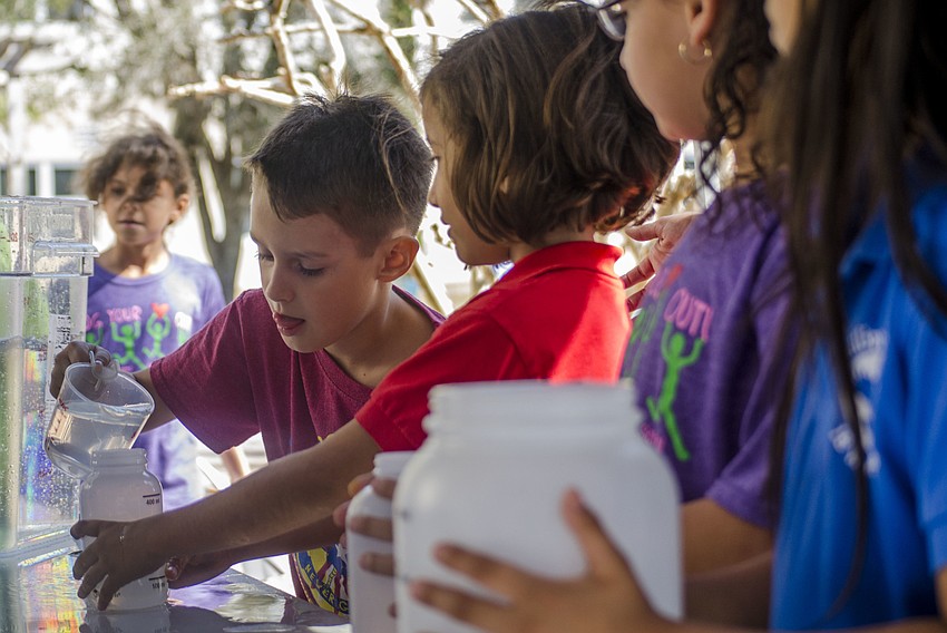 Sebastian Catanese pours water into Taylor Coad'     s container during the water relay portion of the Measurement Olympics.