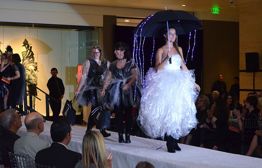 Top three juror’s pick winners Barbara Gerdeman and Elizabeth Goodwill accompany Erin Schineller on the runway as she models “Between the Raindrops” a second time.
