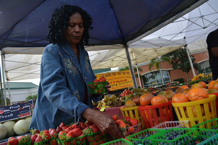 Carrie Dula, with Come Under the Yum Yum Tree, a produce provider, sets up fresh fruits and vegetables for the farmer'   s market.